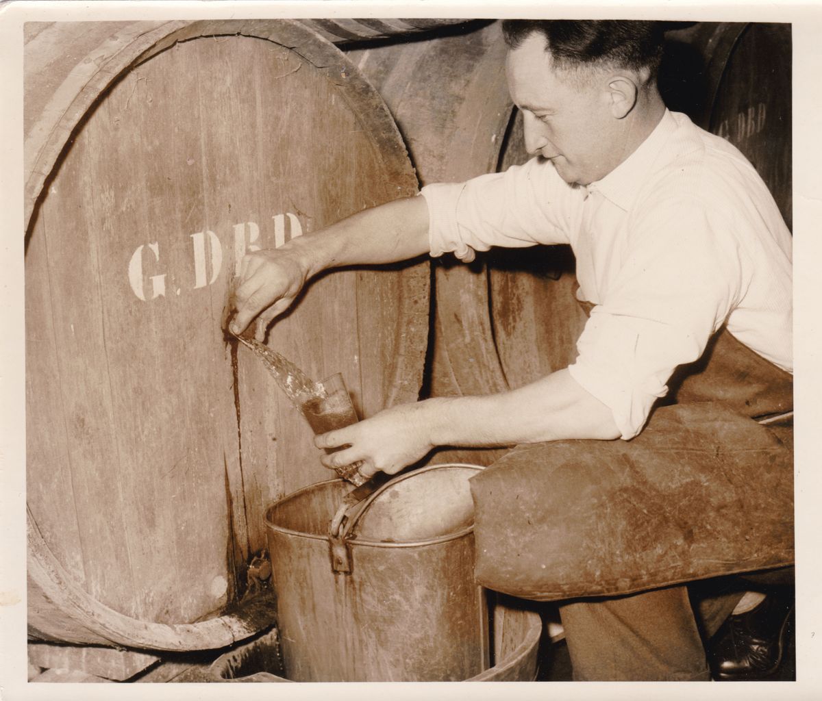 Gaston Debelder taps some lambic from a wooden barrel.